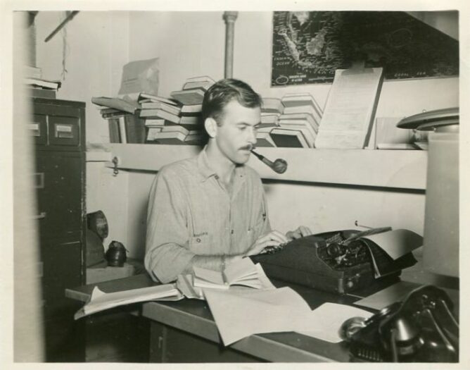 man smoking pipe at a typewriter