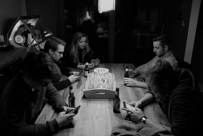 black and white photo of people at table with phone