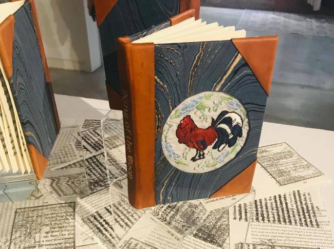 hardcover book with brown and blue marbled cover that includes image of a rooster on front