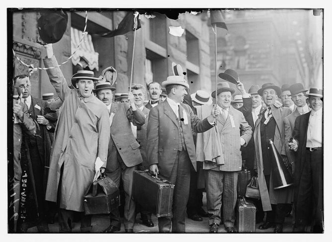 black and white photo of men in suits and pork pie hats celebrating